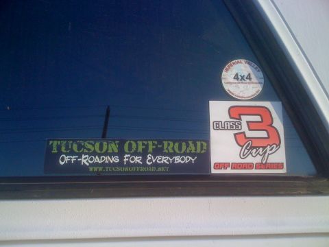 1996 Ford C-350 (Centurion Conversions) - Close-up of club decals on the tinted rear side window of a white vehicle: a green "Tucson Off-Road: Off-Roading For Everybody / www.tucson…