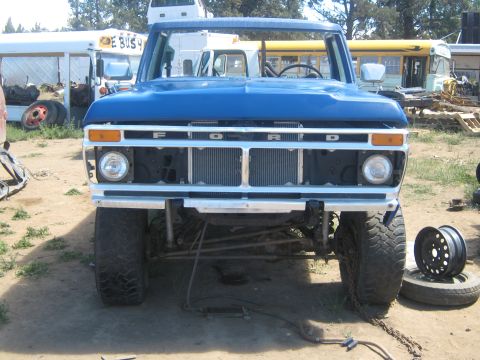 1978 Ford Bronco - Front view of a blue 1978 Ford Bronco, its distinctive grille and headlights, parked in an outdoor lot with other vehicles visible.