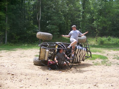 1992 Jeep YJ - Two individuals are seen with an overturned off-road buggy in a wooded area.