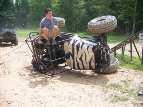 1992 Jeep YJ - An off-road buggy has flipped onto its side, with a person perched on top, while another Jeep is parked nearby.