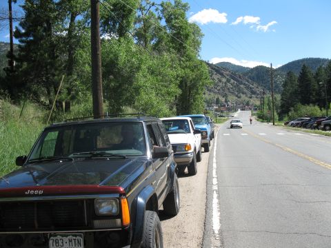 1978 Ford F-150 - Several vehicles are parked along a rural road with mountains in the distance.