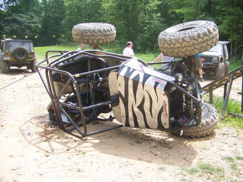 1992 Jeep YJ - An off-road buggy has flipped onto its side, with two other Jeeps visible in the background.