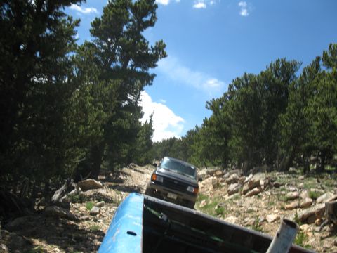 1978 Ford F-150 - Two trucks navigate a rocky mountain trail under a bright blue sky with scattered clouds.