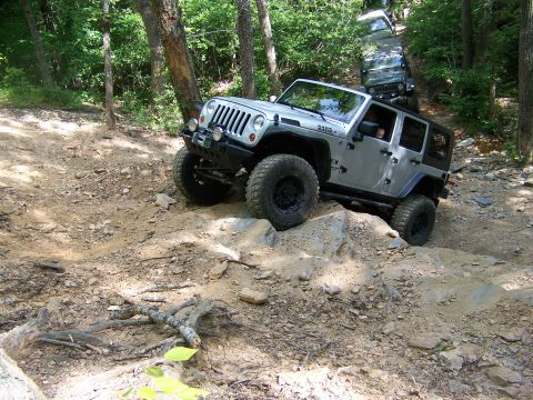 1992 Jeep YJ - Two Jeeps navigate a challenging off-road course on a wooded hillside.