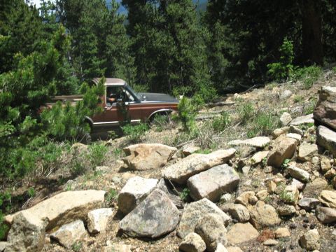 1978 Ford F-150 - Pickup truck driving off-road on a steep, rocky incline in a forested area.