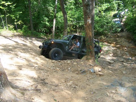 1992 Jeep YJ - A black Jeep Wrangler navigates a challenging off-road trail with other vehicles behind it.