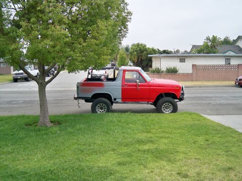 1985 Ford Bronco - A two-tone Ford Bronco sits on the side of a residential street.