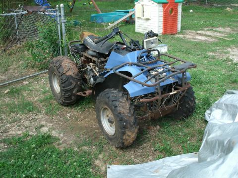 1992 Suzuki QUADRUNNER 250/LT250 - This blue Suzuki ATV appears to be a 1992 model, showing signs of wear and tear with exposed engine components.