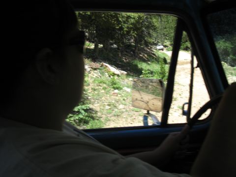 1978 Ford F-150 - Driving on a dirt road through a wooded area, with another vehicle ahead.