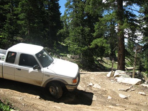1978 Ford F-150 - White pickup truck navigates a rocky, dirt path through a wooded area.