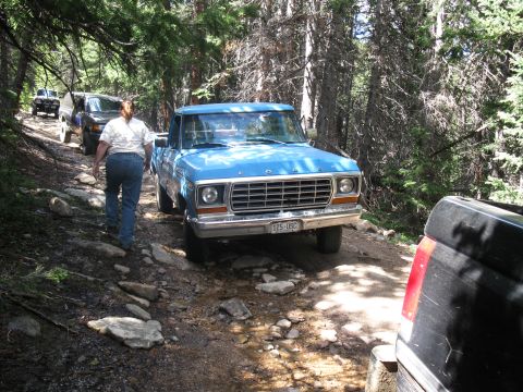 1978 Ford F-150 - A blue 1978 Ford F-150 navigates a rocky mountain path, with other vehicles following in the distance.