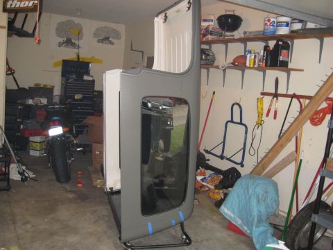 2005 Jeep Wrangler - A Jeep hardtop is stored in a cluttered garage next to a motorcycle and shelves of supplies.
