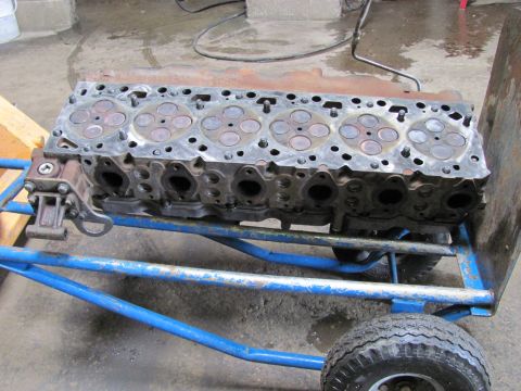 2005 Dodge 3500 - Engine cylinder head on a blue cart in a workshop.