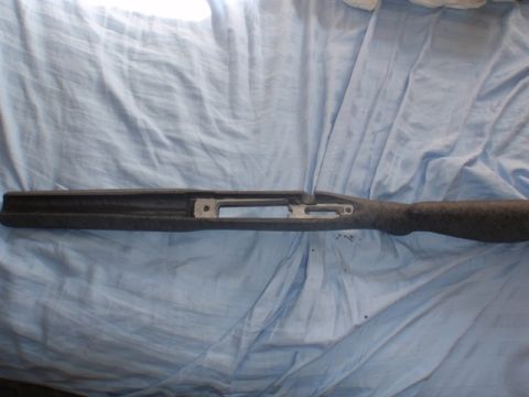 1991 Ford Bronco - A gray speckled gun stock is shown laid out on a blue cloth, revealing the metal receiver housing.