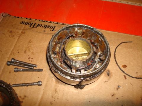 1995 Ford Bronco - A disassembled metal part, likely a vehicle component, lies on a cardboard surface with screws.