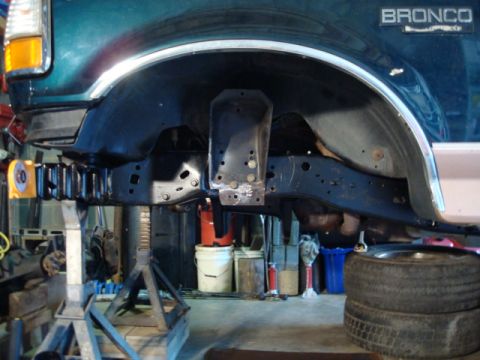 1995 Ford Bronco - The underside of a 1995 Ford Bronco is visible, supported by jack stands in a garage setting.