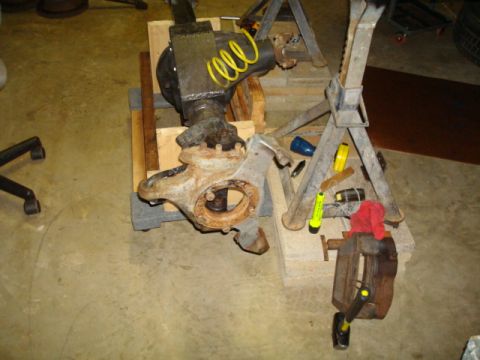 1995 Ford Bronco - A front axle assembly, likely from a truck or SUV, is shown disassembled and supported by wooden blocks and jack stands in a workshop.
