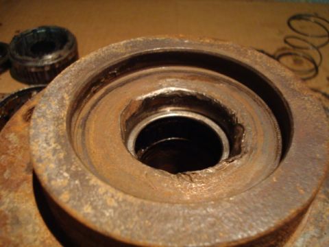 1995 Ford Bronco - Rusted wheel hub assembly with damaged bearing race and loose bearing. Part of a vehicle's suspension system.