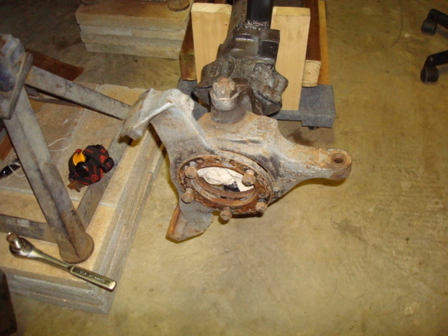 close-up of a rusty vehicle front axle assembly with a wrench nearby
