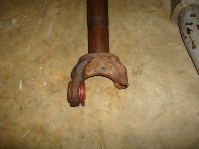 Rusted driveshaft yoke with red bushing, on a concrete floor