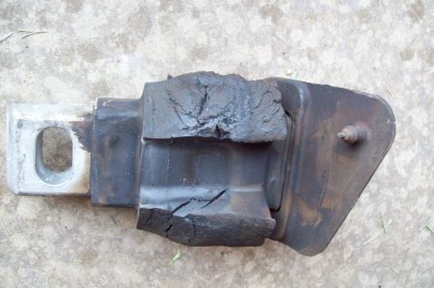 2006 Ford Fusion - A removed engine mount lying on concrete, its black rubber insulator deeply cracked and splitting away from the stamped-steel bracket on bo…