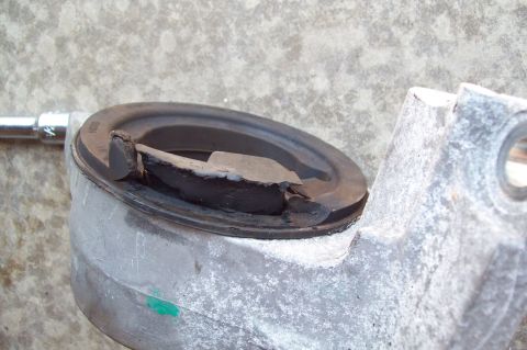 2006 Ford Fusion - Close-up of a metal cup-shaped mount or bearing housing held in a vise, filled with old dark grease being scraped out. A chrome socket exte…