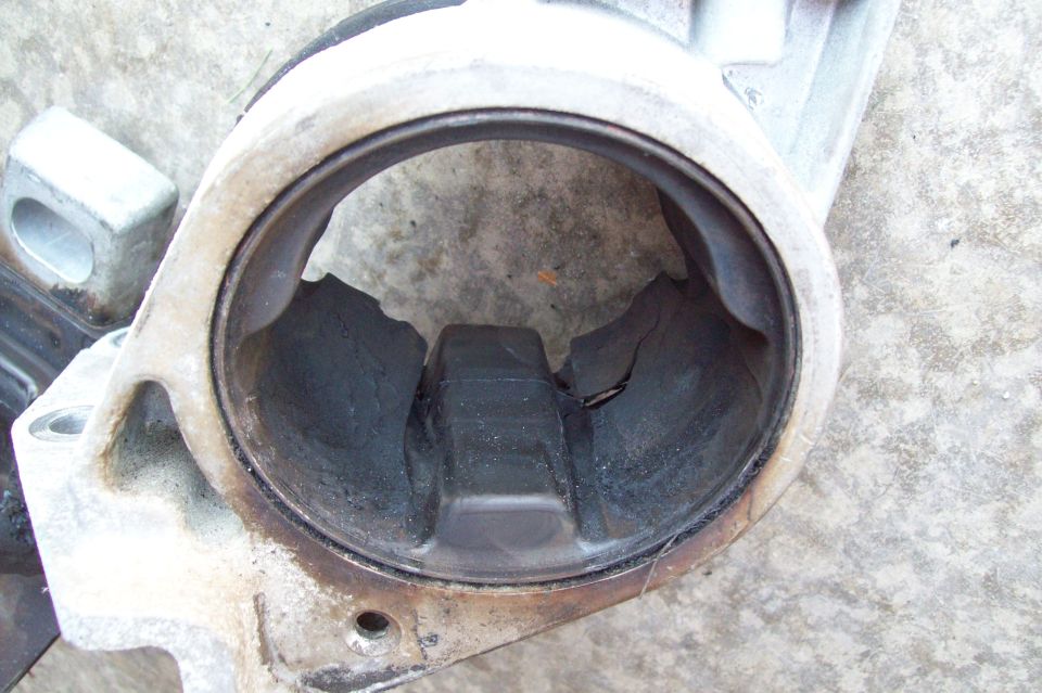Carbon-caked round aluminum engine part on concrete