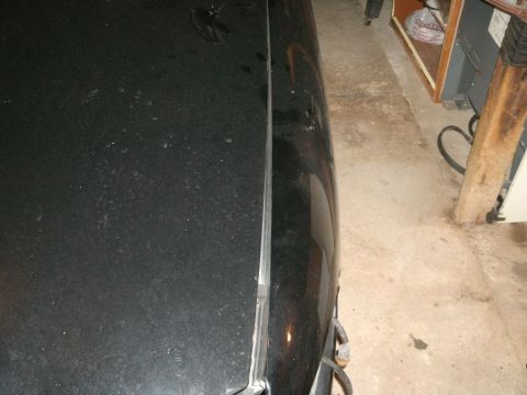 1998 Lincoln Mark VIII - A close-up view of a car's hood seam, revealing a portion of the vehicle's bodywork in a garage setting.