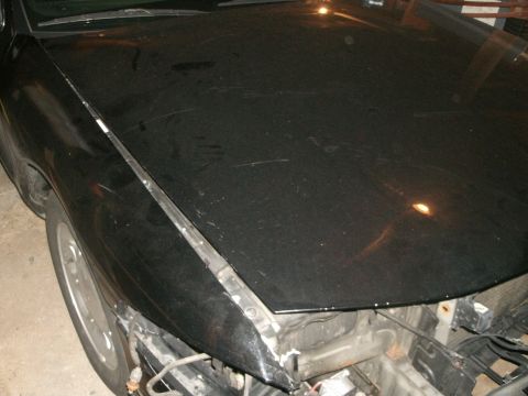 1998 Lincoln Mark VIII - Front view of a black car's damaged hood and fender, showing significant wear and tear.