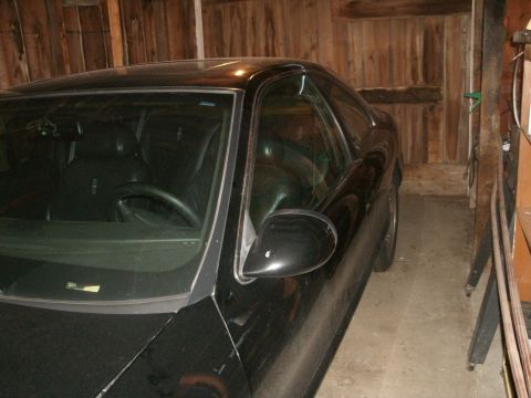 1998 Lincoln Mark VIII - The front passenger side of a black 1998 Lincoln Mark VIII is visible, parked in a rustic wooden garage.