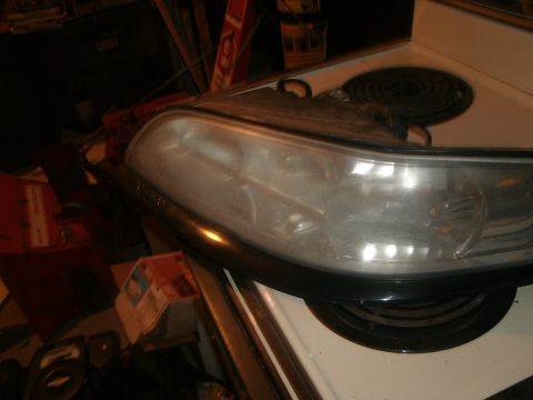 1998 Lincoln Mark VIII - A headlight assembly rests on a kitchen stovetop, with various items in the background.