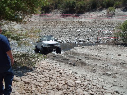 1986 Ford Bronco - Suzuki Samurai navigates a rocky stream bed during an off-road excursion.