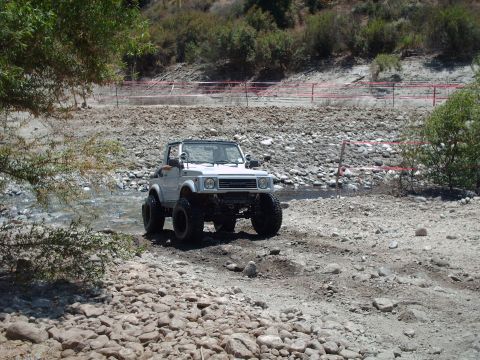 1986 Ford Bronco - This off-road vehicle navigates a challenging, rocky terrain with a stream running through it.