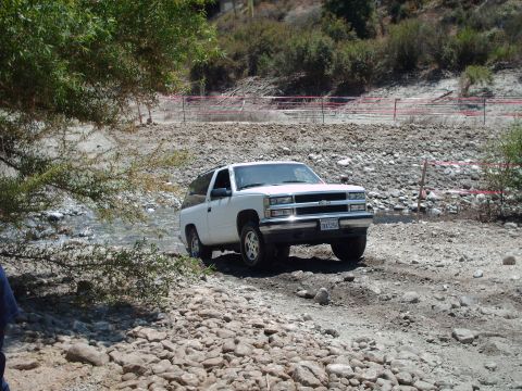 1986 Ford Bronco - This 1995 Chevrolet Tahoe is navigating a challenging off-road terrain with a rocky stream.