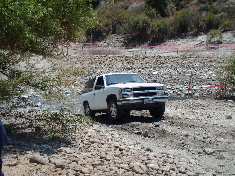 White Chevrolet Tahoe driving through a rocky stream bed