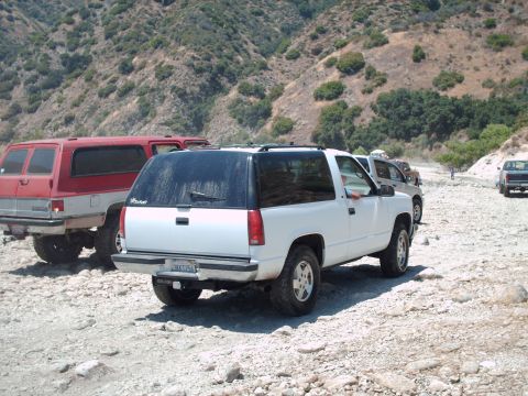 1986 Ford Bronco - A white SUV is parked on a rocky surface with a red SUV behind it.