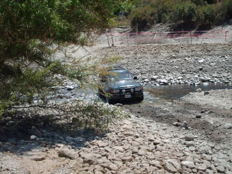 1986 Ford Bronco - SUV navigates a rocky stream, suggesting off-road capability.