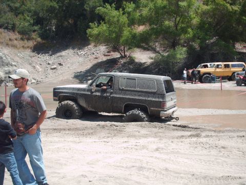 1986 Ford Bronco - This muddy SUV is stuck in the mud during an off-road event, with another vehicle visible in the background.