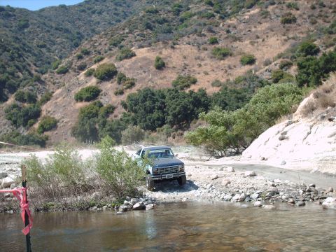 1986 Ford Bronco - 1986 Ford Bronco navigating a shallow water crossing on a dirt road.