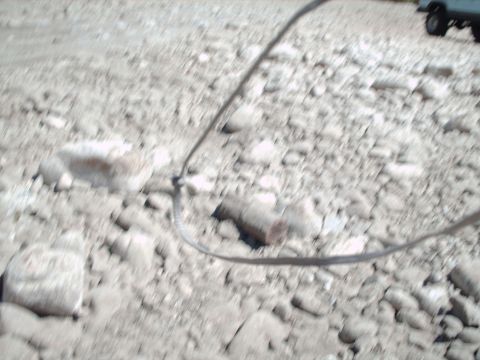 1986 Ford Bronco - A cable lies on a rocky, outdoor surface.