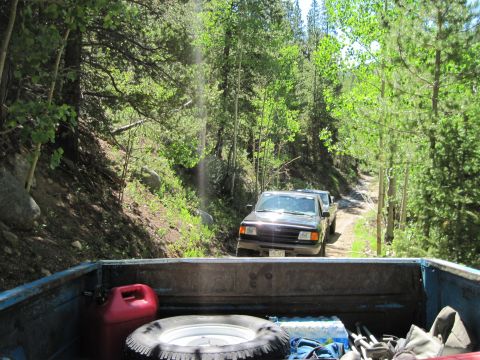 1978 Ford F-150 - Two trucks on a dirt road in a wooded area, one seen from the bed of the other.