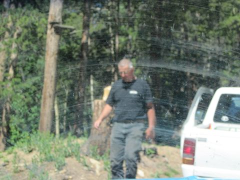 1978 Ford F-150 - A man stands beside a white pickup truck with its driver's side door ajar, set against a backdrop of trees.