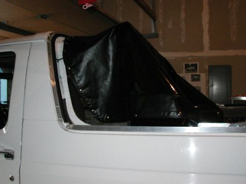 1995 Ford Bronco - A white 1995 Ford Bronco is shown from the side, partially covered by a black soft top.