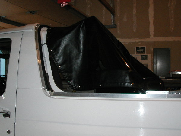 White Ford SUV side view in garage with black soft top removed and propped up
