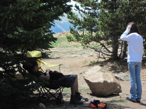 1978 Ford F-150 - Two people enjoy a scenic mountain view while relaxing in camping chairs under pine trees.