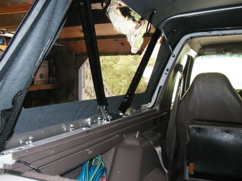 1995 Ford Bronco - The interior of a vehicle shows the framework and straps for a soft top installation.