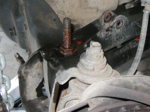1995 Ford Bronco - Close-up of a rusty bolt and nut on a vehicle's suspension component, likely during repair.