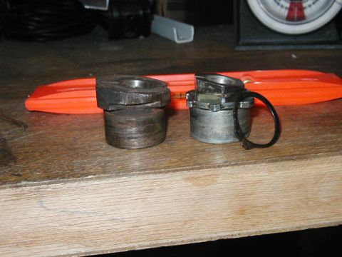 1995 Ford Bronco - Two metal suspension components are displayed on a wooden workbench, with an orange object in the background.