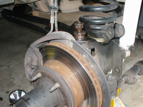 1995 Ford Bronco - Vehicle's front suspension and brake assembly, including rotor, caliper, and coil spring.