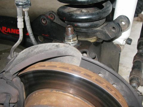 1995 Ford Bronco - Close-up of vehicle suspension components, including a brake rotor and coil spring.